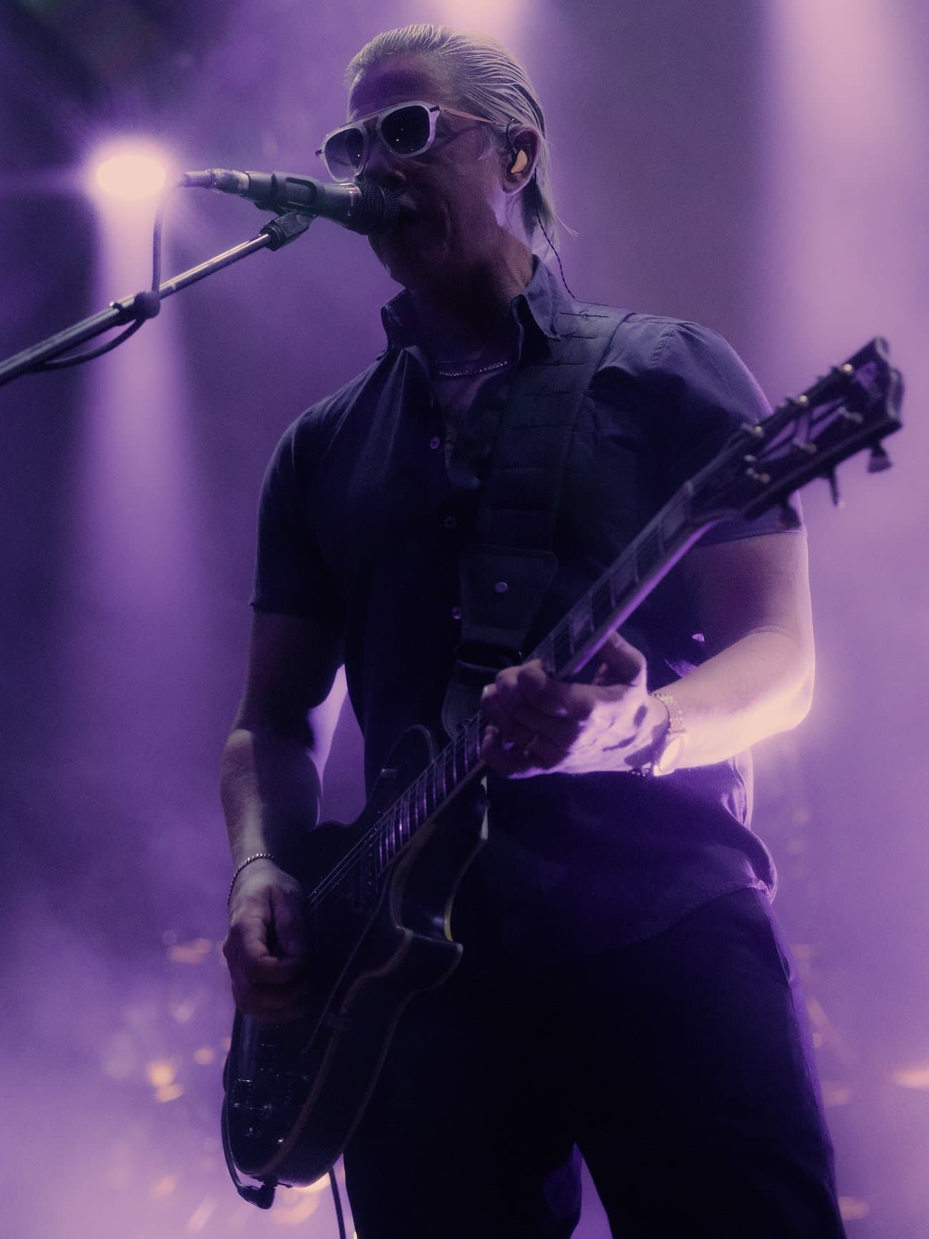 Guitarist performing in purple stage light